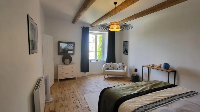 Chambre rénovée en bâti ancien, poutres apparentes et parquet en bois massif